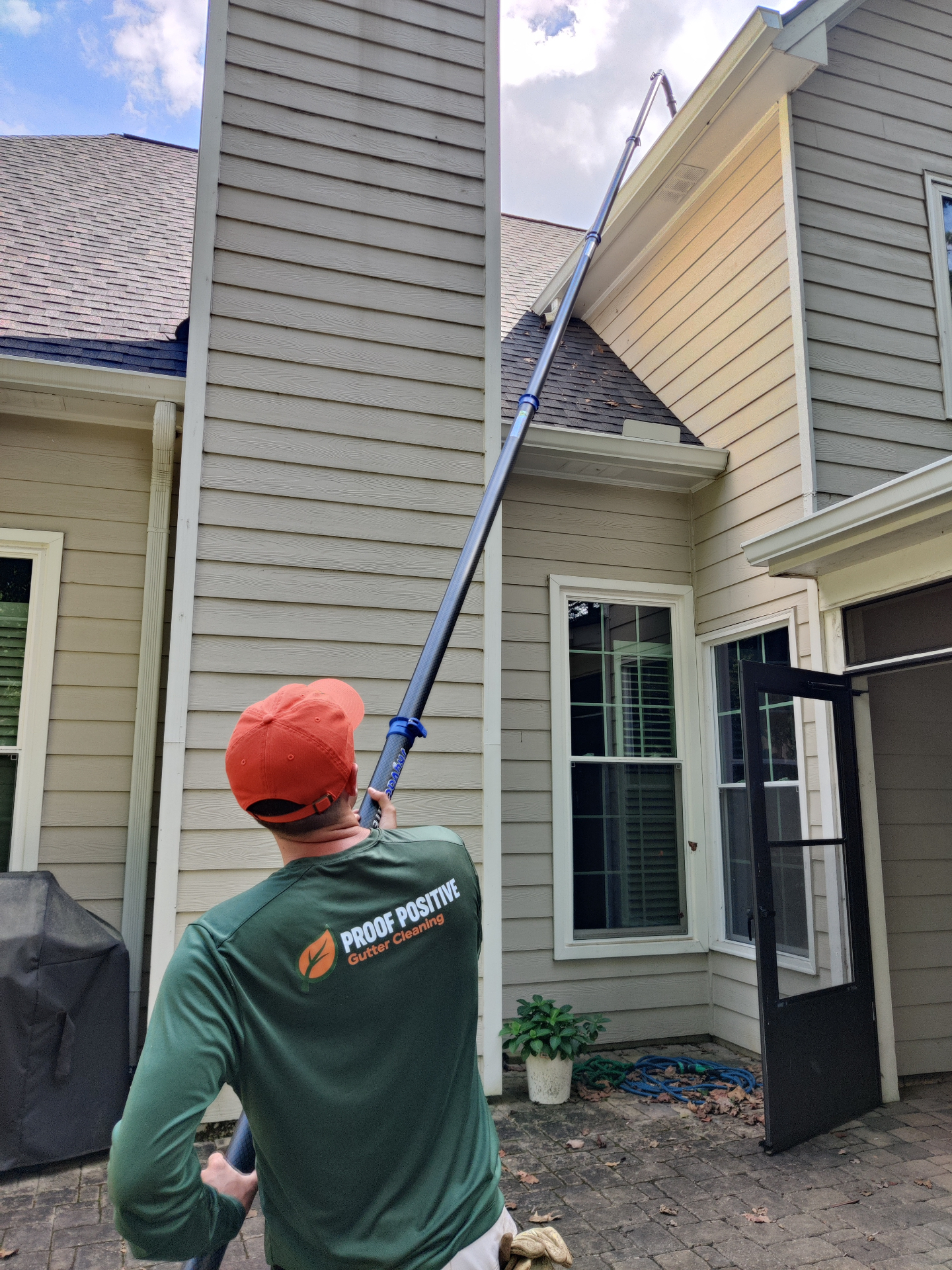 Proof Positive technician cleaning gutters from the ground with a long vacuum pole