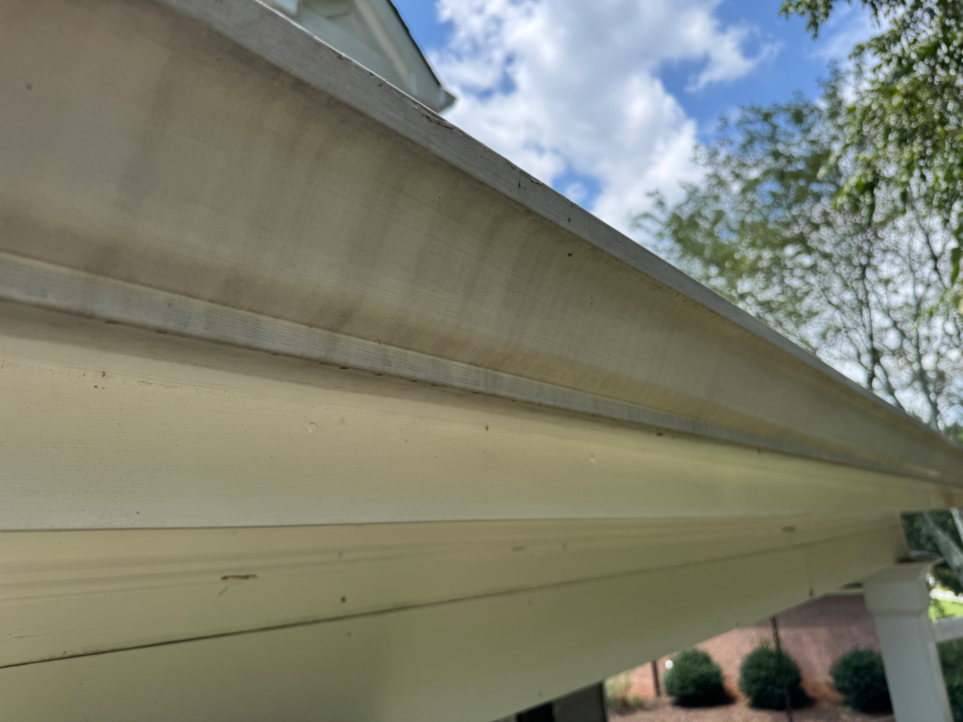 Underside of white aluminum gutters showing dark vertical tiger striping streaks baked into the finish